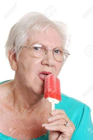 This meme features an image of a woman, likely in her older age, with a surprised and slightly disapproving expression. She's holding a brightly colored popsicle, and the text "I'm not crying, I'm just allergic to happiness" is written above her. The image is meant to be humorous, implying that the woman is trying to appear stoic but is actually overcome with emotion.
